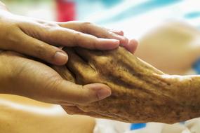 hold the elderly man's hand in a hospice