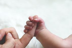 newborn tiny hand holding father's finger