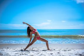 girl in bikini in yoga pose on the beach