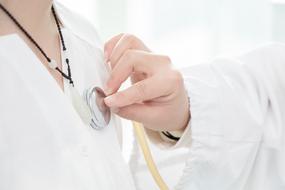 nurse is, listening to a patient with a stethoscope
