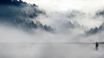 photo of a broken-hearted man on the shore of a foggy lake