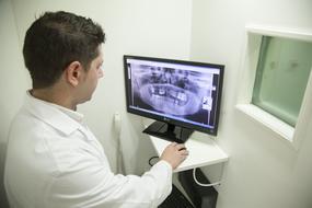 the doctor analyzes the x-ray of the jaw on a computer