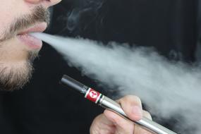 Man vaping e cigarette at dark background