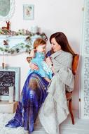 photo of mom with her daughter on the background of a cozy interior
