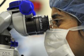 man in mask looking at microscope, doctor
