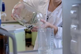 pour water into a measuring vessel in a laboratory