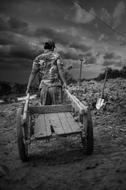 Poor Man with wheelbarrow in countryside