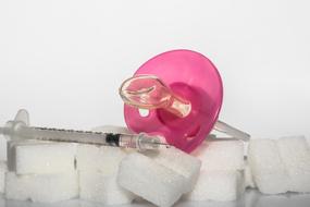 Diabetes With Toddler, pacifier and insulin syringe on pile of sugar