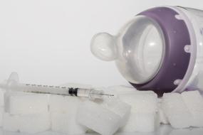 syringe and baby bottle lie on sugar