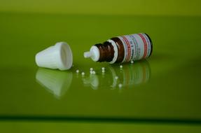 bottle with Homeopathy Beads on green glass