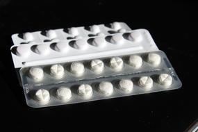 white pills in a blister on a black background