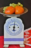 tangerines and grapes on a kitchen scale