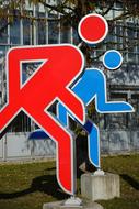 Two red and blue running figures near the building