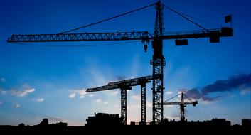 construction cranes against the blue sky at sunrise