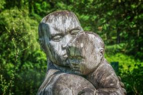 wooden sculpture of a father with a child in the park