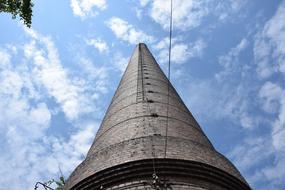 Low angle shot of a chimney, at beautiful background with blue sky and white clouds