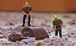 Miniature figures of the workers, with the tools, on the chocolate piece