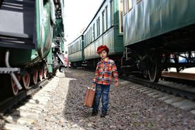 cute child with a suitcase among the trains