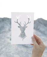 stencil in the form of a deer on a background of mountains