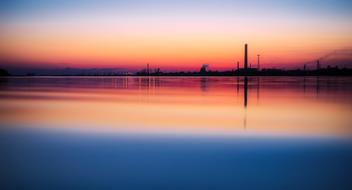 distant view of an industrial plant near the water at dusk