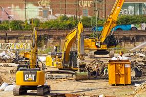 Yellow, black and white "CAT" excavators on demolition work, on the site