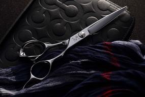Close-up of the shiny metal scissors, near the colorful cloth
