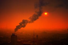 Smoke from industrial chimney above city at Sunset