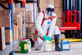 man in Protection Costume works with dangerous liquids in store