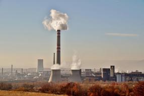 Chemical factory with the smoke among the colorful plants in Czech Republic in autumn