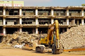 excavator against the background of a dismantled building
