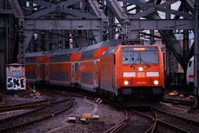 Orange train, with the reflections in the windows, on the railway, near the colorful graffiti