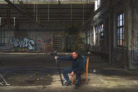 photographer with camera on a chair in an abandoned factory