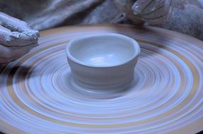Potter, making beautiful, white and orange, shiny pot