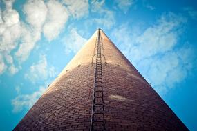 Low angle shot of the chimney building in light and shadow, under the blue sky with white clouds