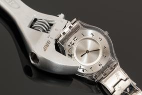 Close-up of a metal wristwatch and shifting spanner, with reflections