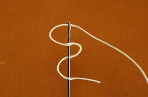 white thread and needle on a brown background