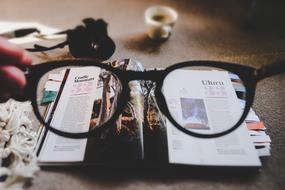 Eyeglasses in hand above book