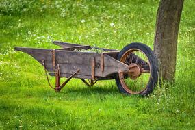 old wooden wheelbarrow on green grass