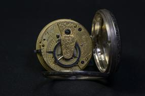 brass pocket watch on black