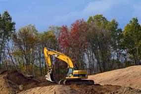 Yellow machine on the construction among the colorful plants