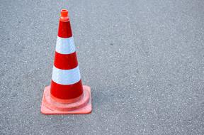 striped road cone on the pavement