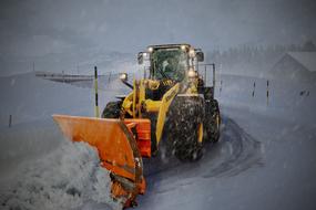 yellow tractor removes snow