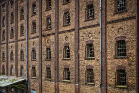 Old brick industrial building with grated windows, detail of facade