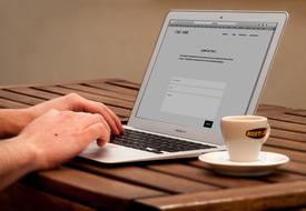 Macbook and white cup with the plate on wooden table