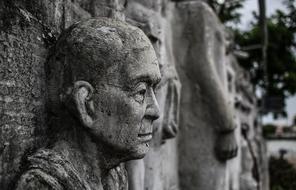 Head of weathered male stone sculpture at wall, thailand, bangkok