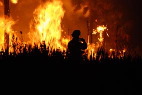 silhouette of a firefighter on a background of fire on the field