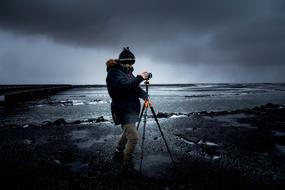 Photographer with Camera on Tripod at sea on stormy weather