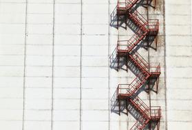 red metal staircase on grey concrete wall of Factory Building, Lithuania