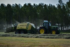 a tractor with a tug collects hay from the field