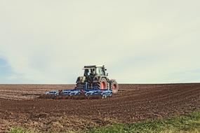 Beautiful landscape with the brown and green arable field with the tractor